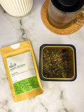 Load image into Gallery viewer, Immunitea product in green package with loose leaf herbs and a mug of tea
